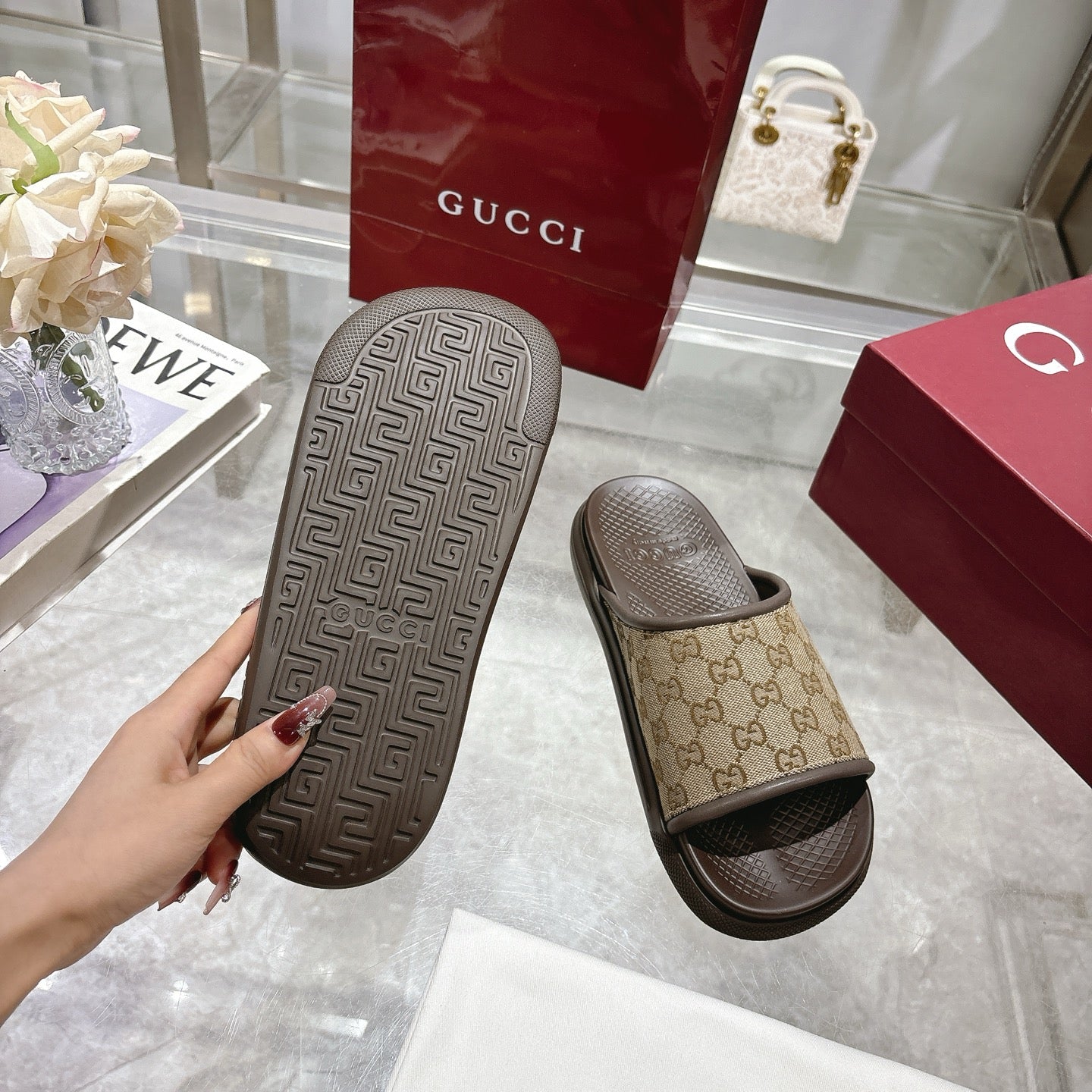 Gucci GG slide sandals outsole view, textured dark rubber tread and tan strap
