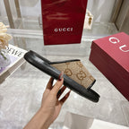Gucci slide sandal side view with tan GG canvas strap and black rubber sole