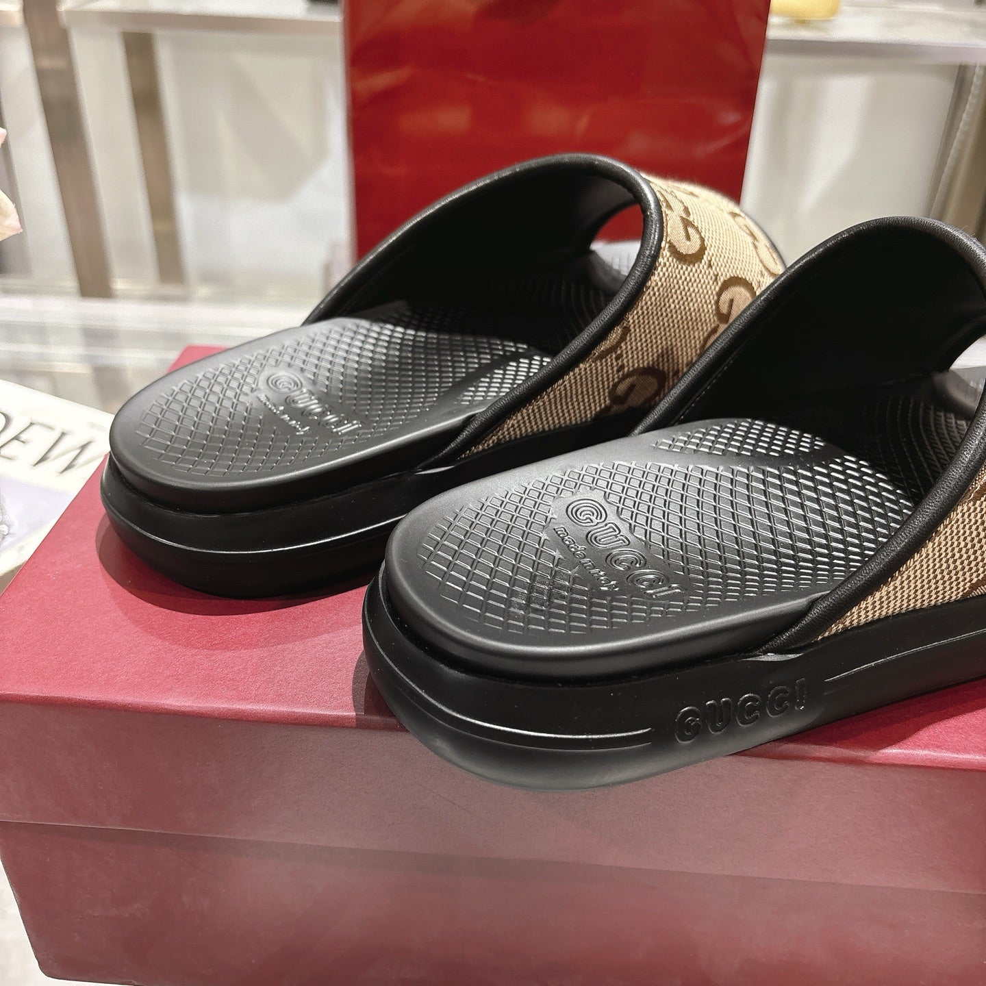 Gucci slide sandals close-up: black textured footbeds with tan GG strap