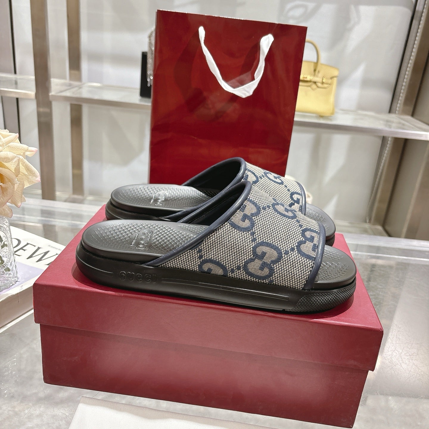 Gucci slide sandals with GG monogram upper and black rubber footbed, blue and cream.