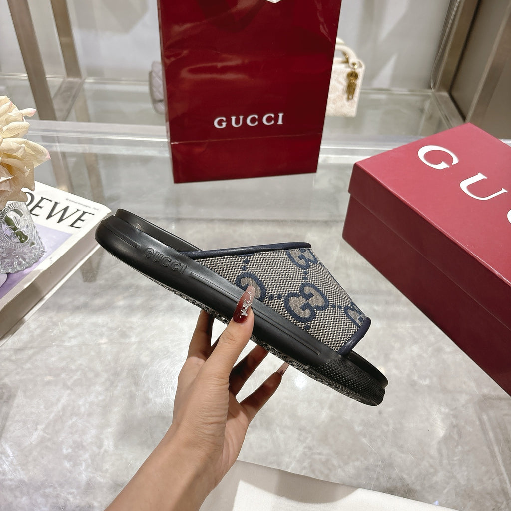 Gucci slide sandals side view, GG monogram upper with black rubber sole and strap.