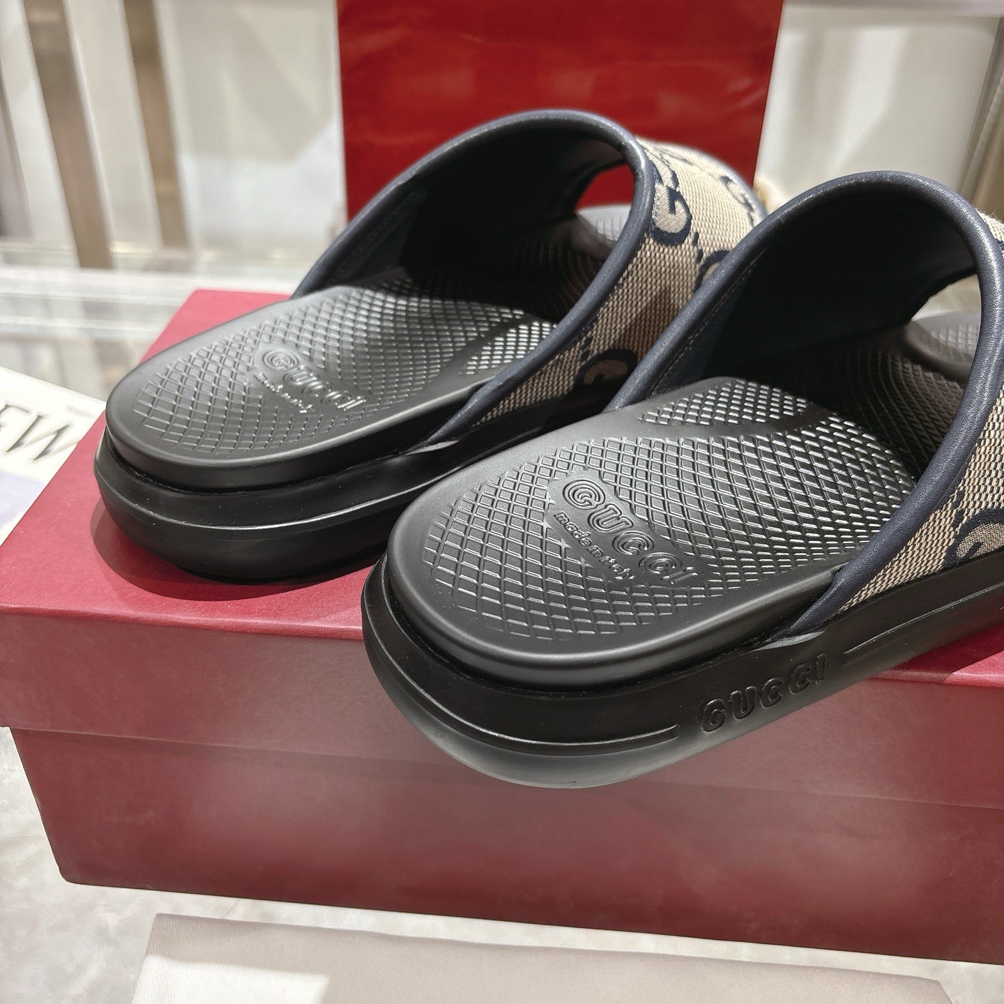 Gucci slide sandals close-up, black textured footbeds with GG monogram strap.