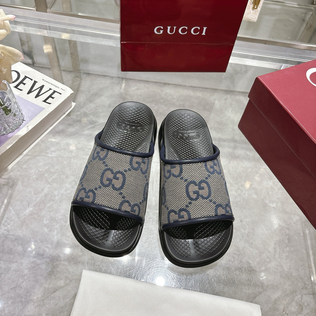 Pair of Gucci slide sandals, GG monogram fabric uppers with black rubber soles.