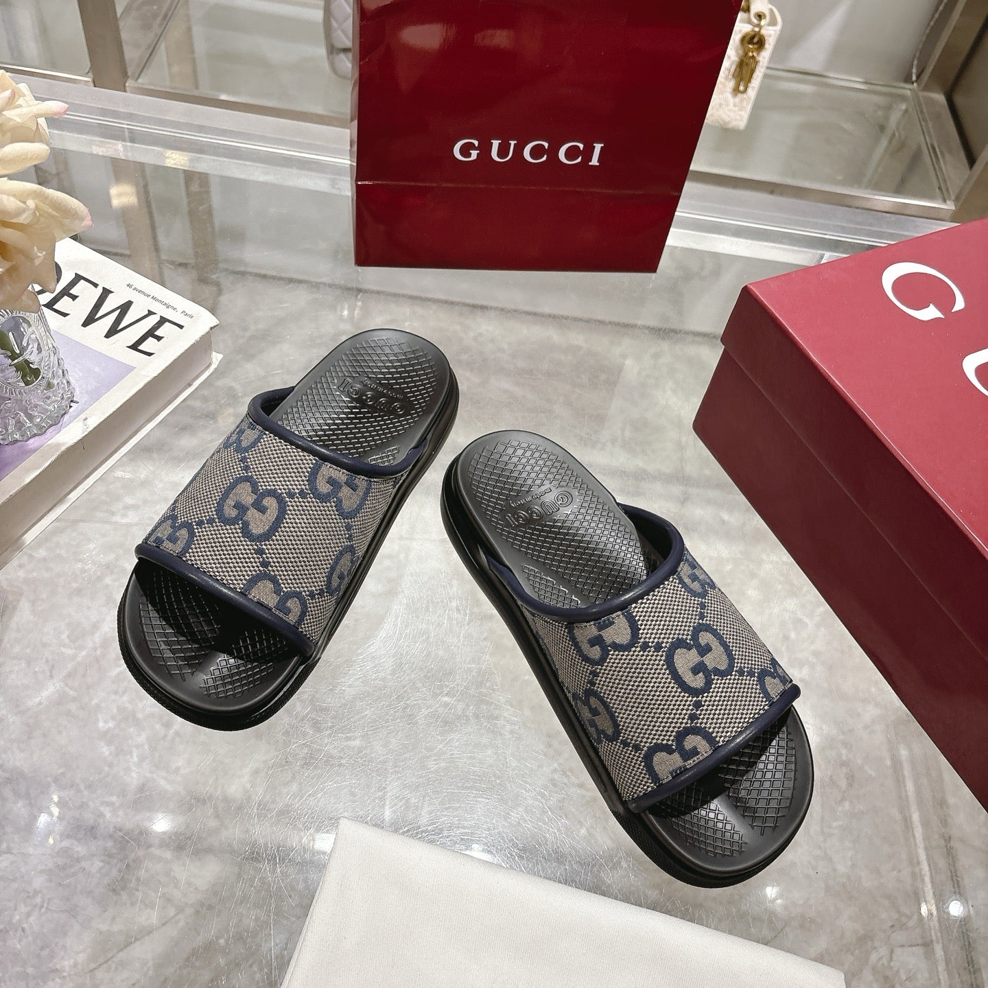 Gucci slide sandals, GG monogram canvas straps with textured black rubber soles.