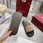 Beige GG canvas slide sandals with dark outsole tread, held for display