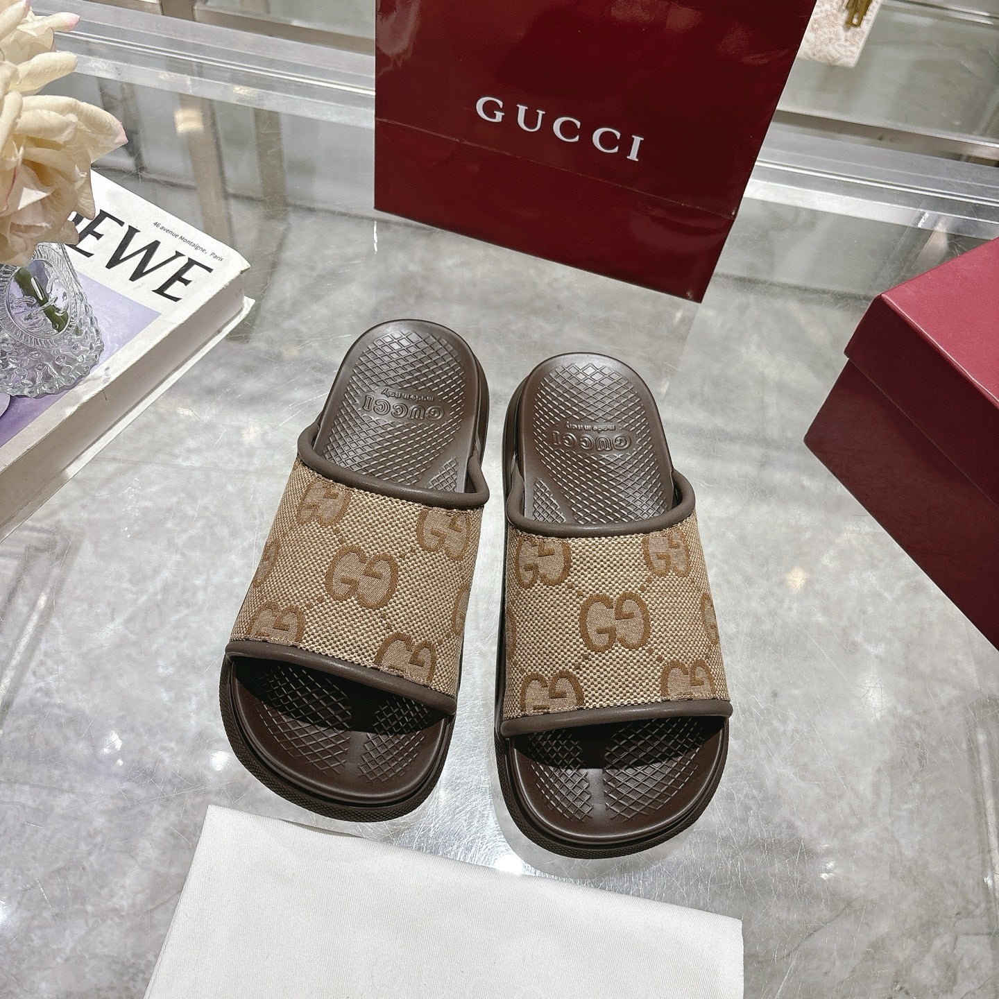 Pair of beige GG canvas slide sandals with dark textured footbeds