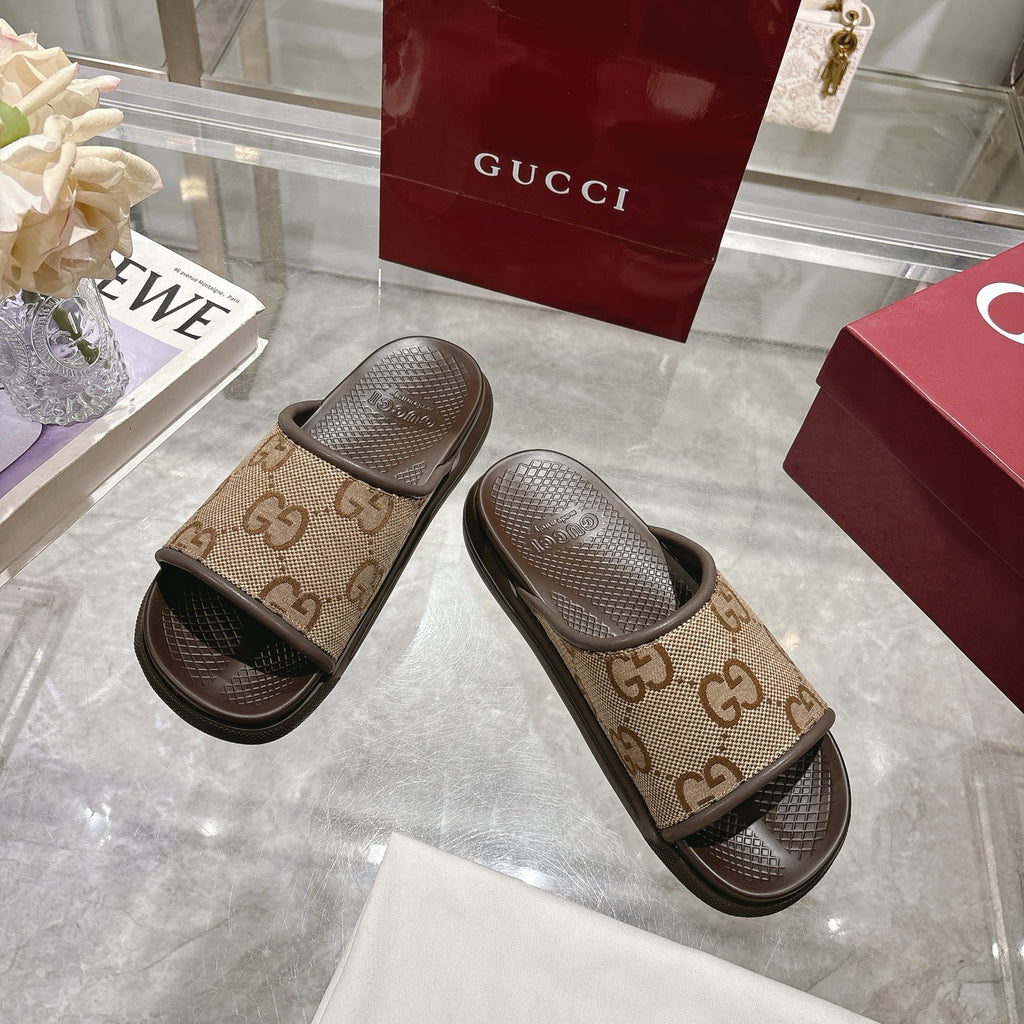 Beige GG canvas slide sandals with dark rubber trim and textured footbeds