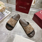 Beige GG canvas slide sandals with dark rubber trim and textured footbeds