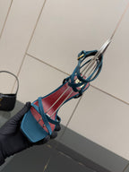 YSL ladies’ strappy heeled sandal held close-up, blue with red trim and thin straps