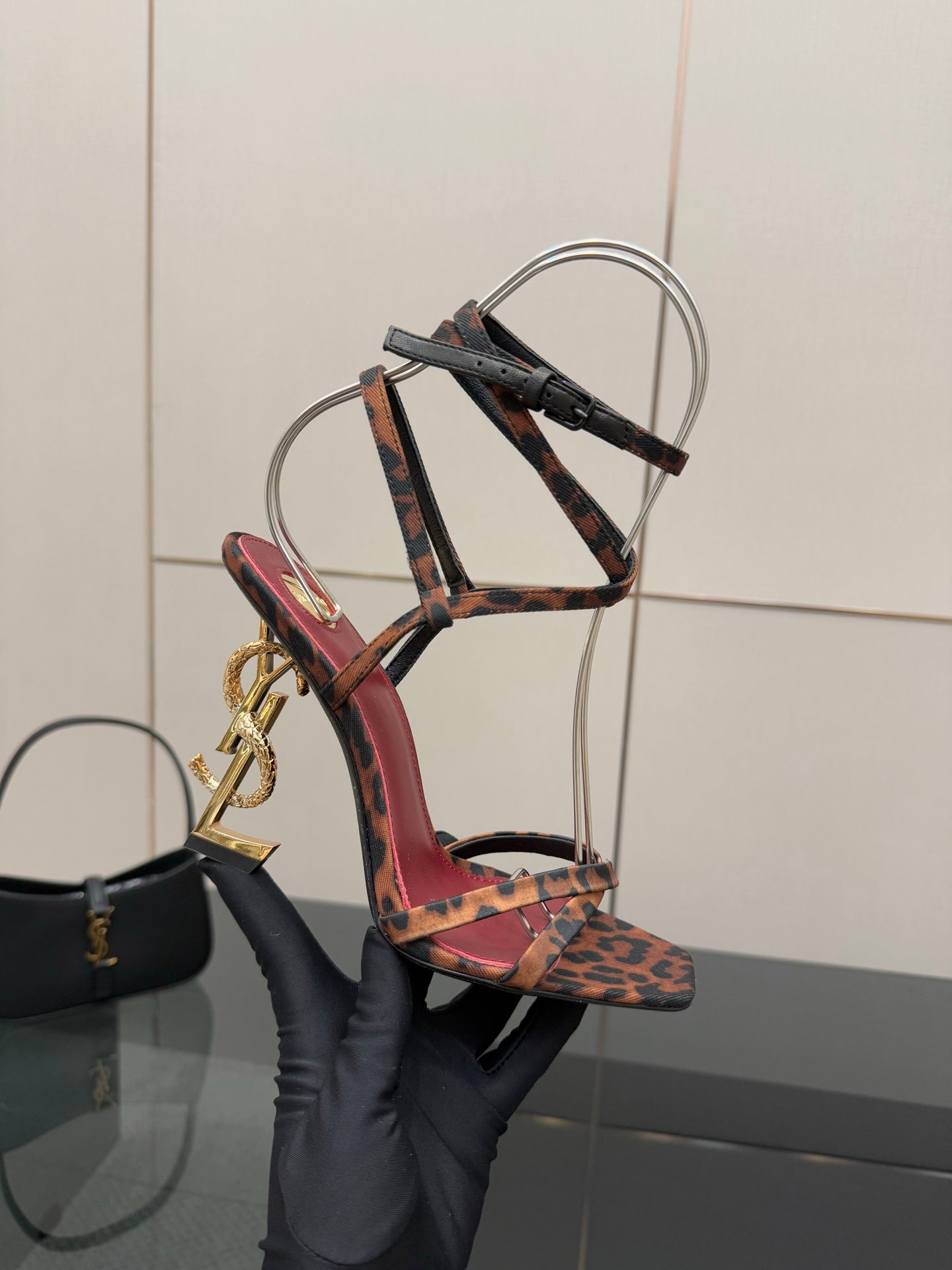 Side view of leopard print strappy high-heel sandal with gold logo heel detail