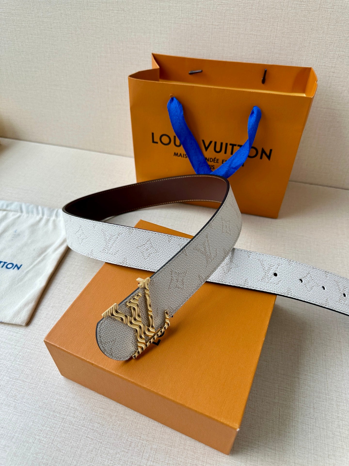 Louis Vuitton belt on box: light gray textured strap with dark brown underside