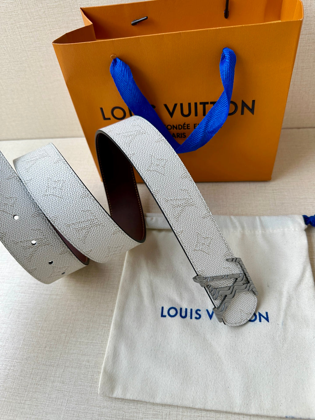 Louis Vuitton belt shown rolled: light gray strap with dark brown inner side