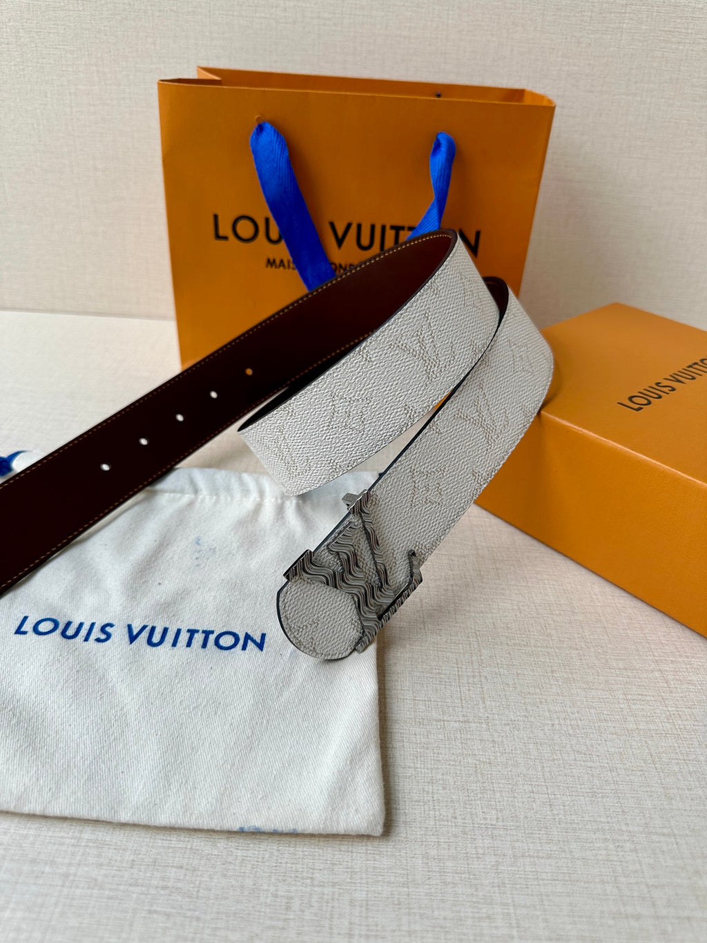 Louis Vuitton belt on dust bag: light gray textured strap with dark brown underside