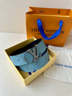 Blue monogram belt with gold buckle in open box, with pouch beside it.
