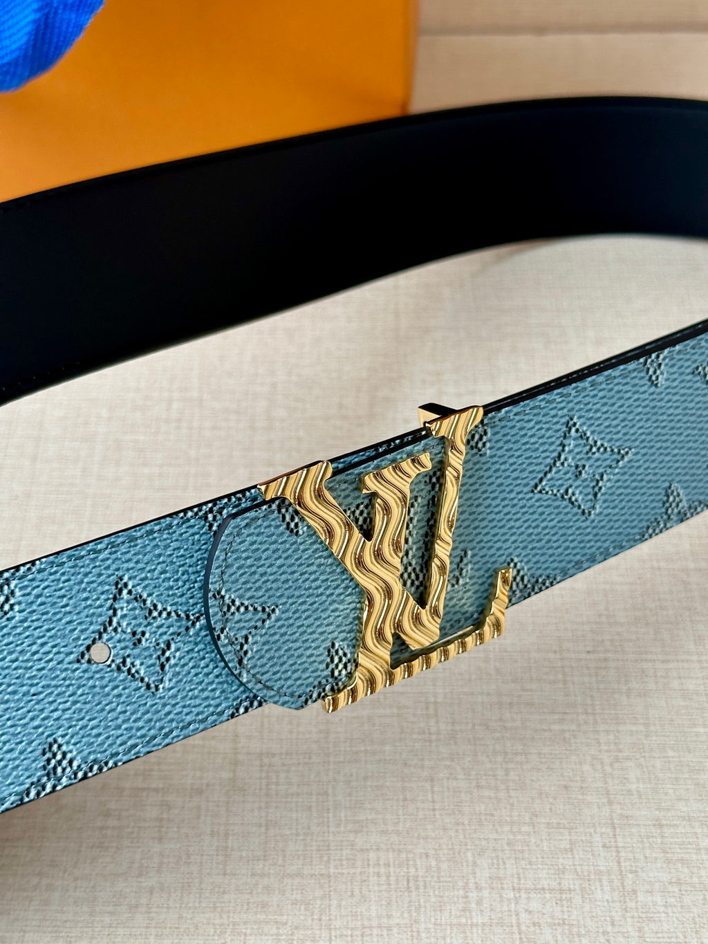 Blue monogram belt with gold buckle detail and black inner lining.