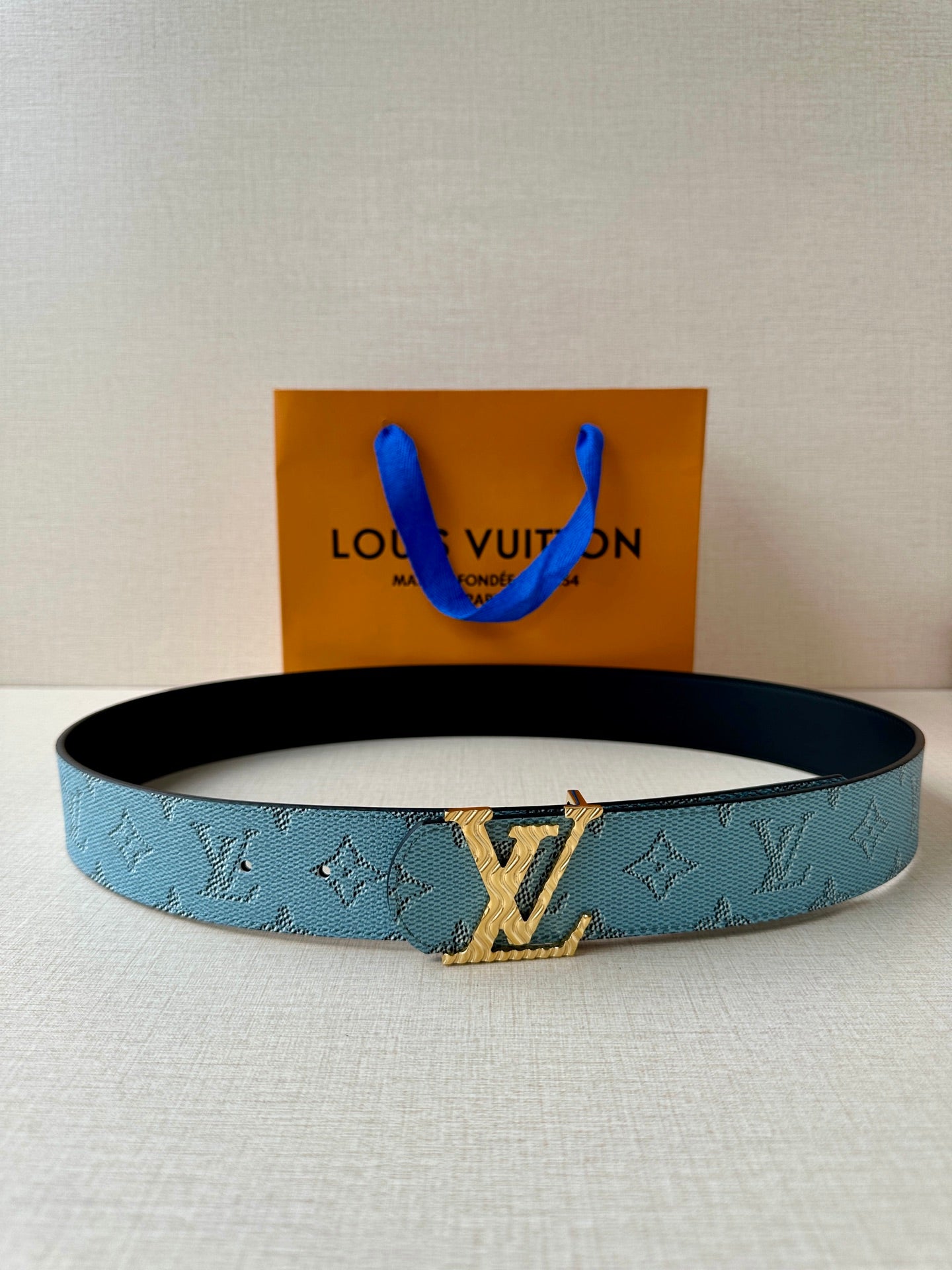 Louis Vuitton belt, blue monogram strap with gold buckle and black underside.
