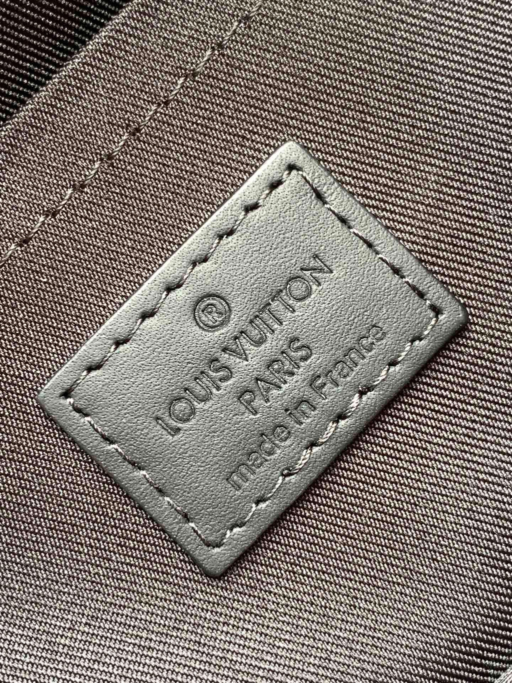 Leather luggage tag patch with stitched edges and printed Louis Vuitton wording