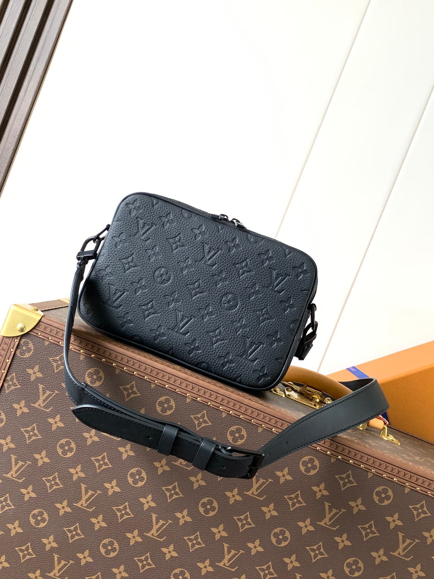 Dark monogram leather crossbody bag with front flap, crossbody strap, and hardware