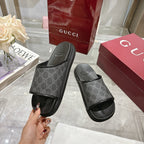 Monogram slide sandals with dark patterned upper, wide strap, and textured rubber footbed