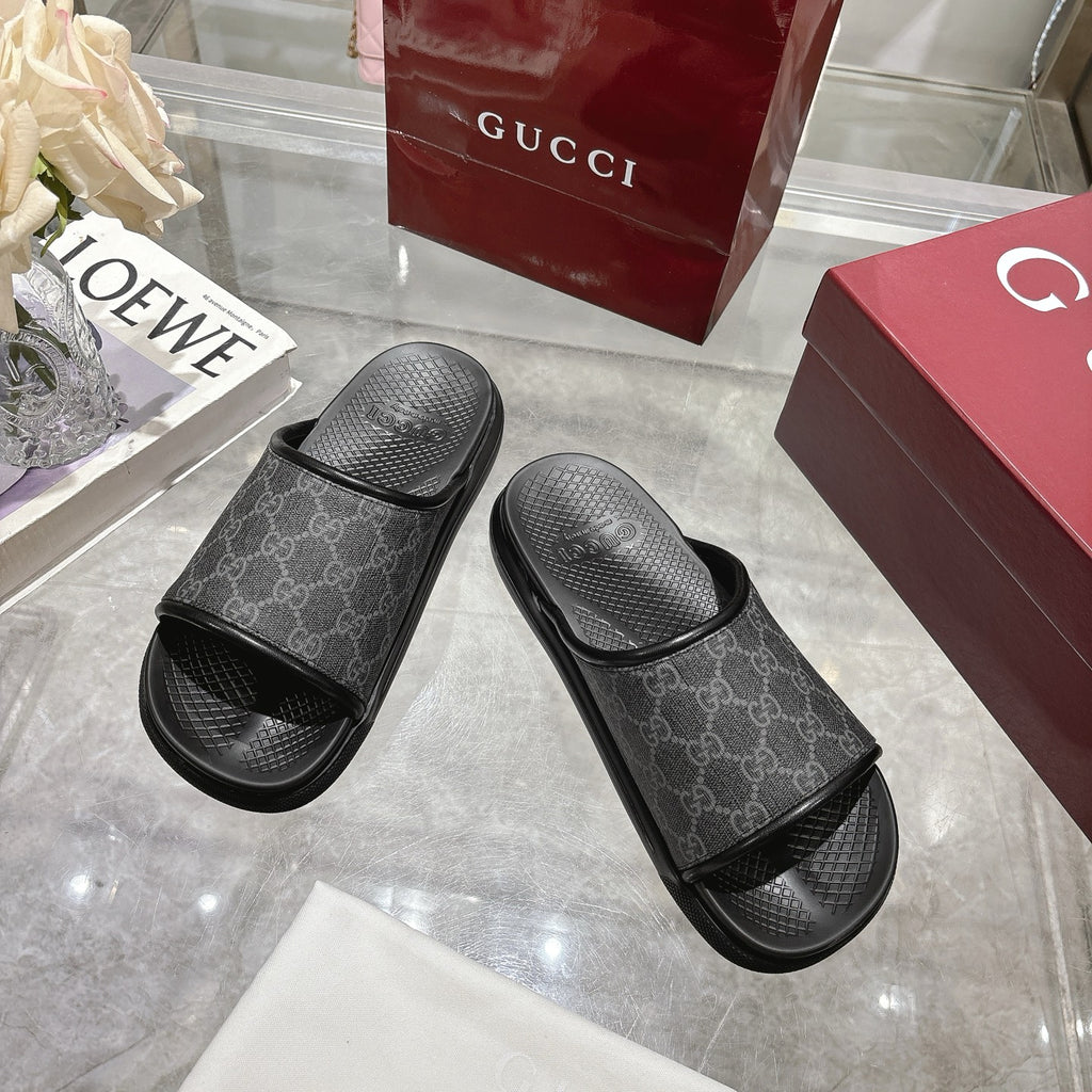 Monogram slide sandals pair with dark patterned upper, wide strap, and textured rubber footbed