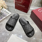 Monogram slide sandals pair with dark patterned upper, wide strap, and textured rubber footbed