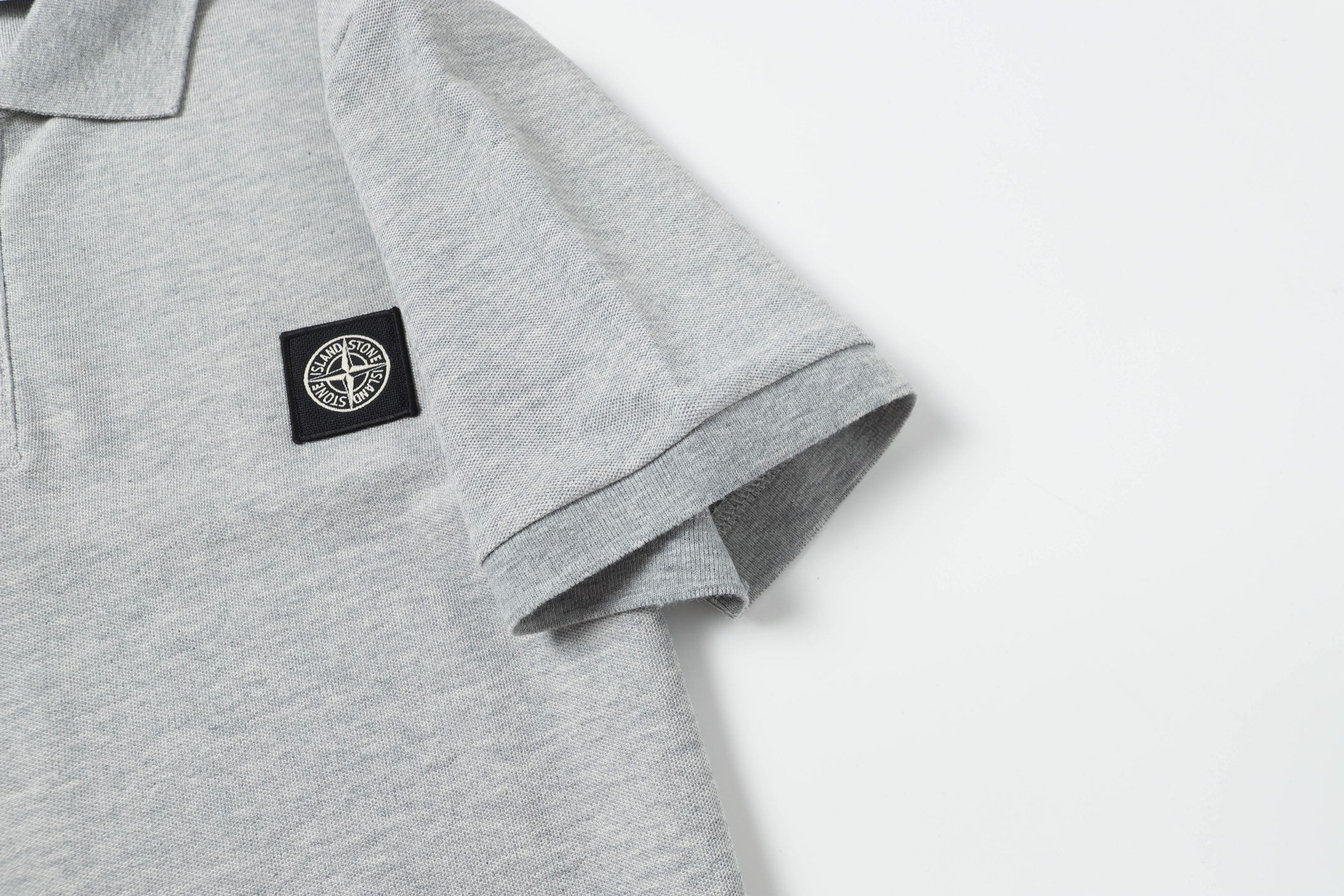 Light gray polo sleeve cuff with small logo patch