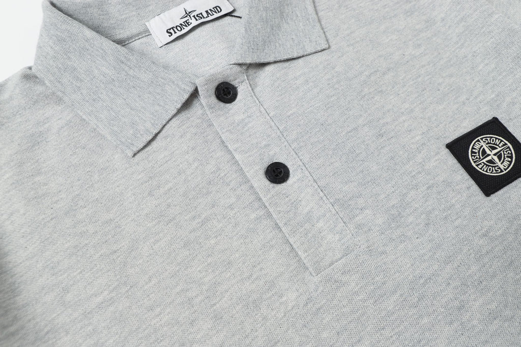 Light gray polo shirt front with black buttons and side logo patch
