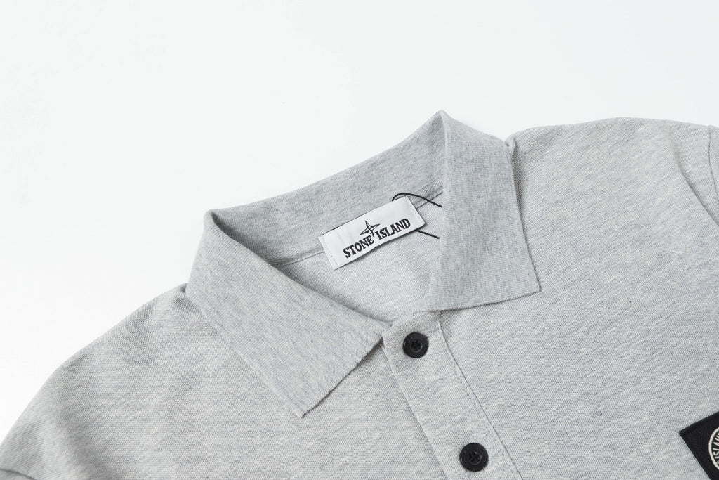 Light gray polo shirt collar with black buttons and tag