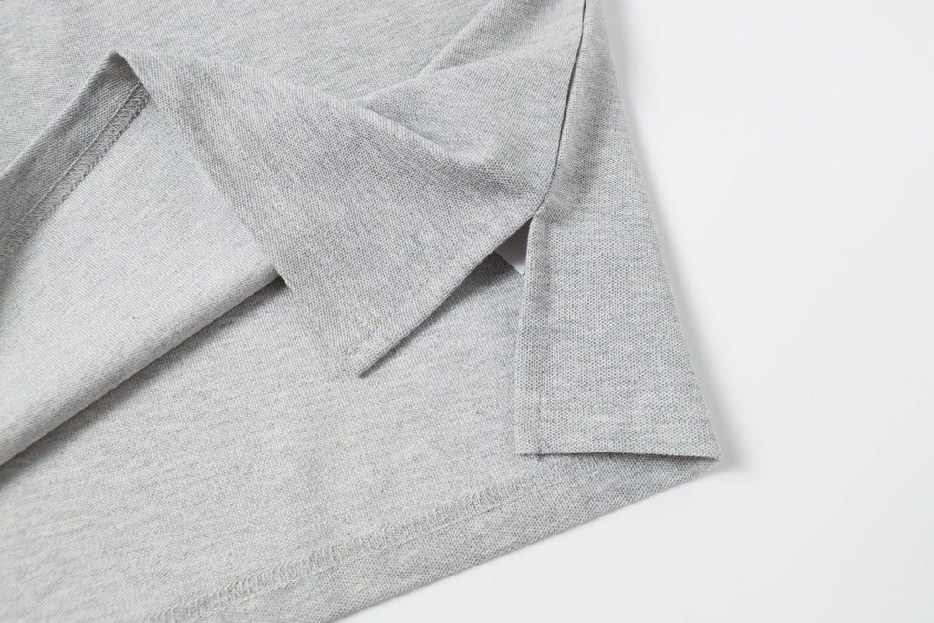 Light gray polo shirt hem with side seam and button placket detail