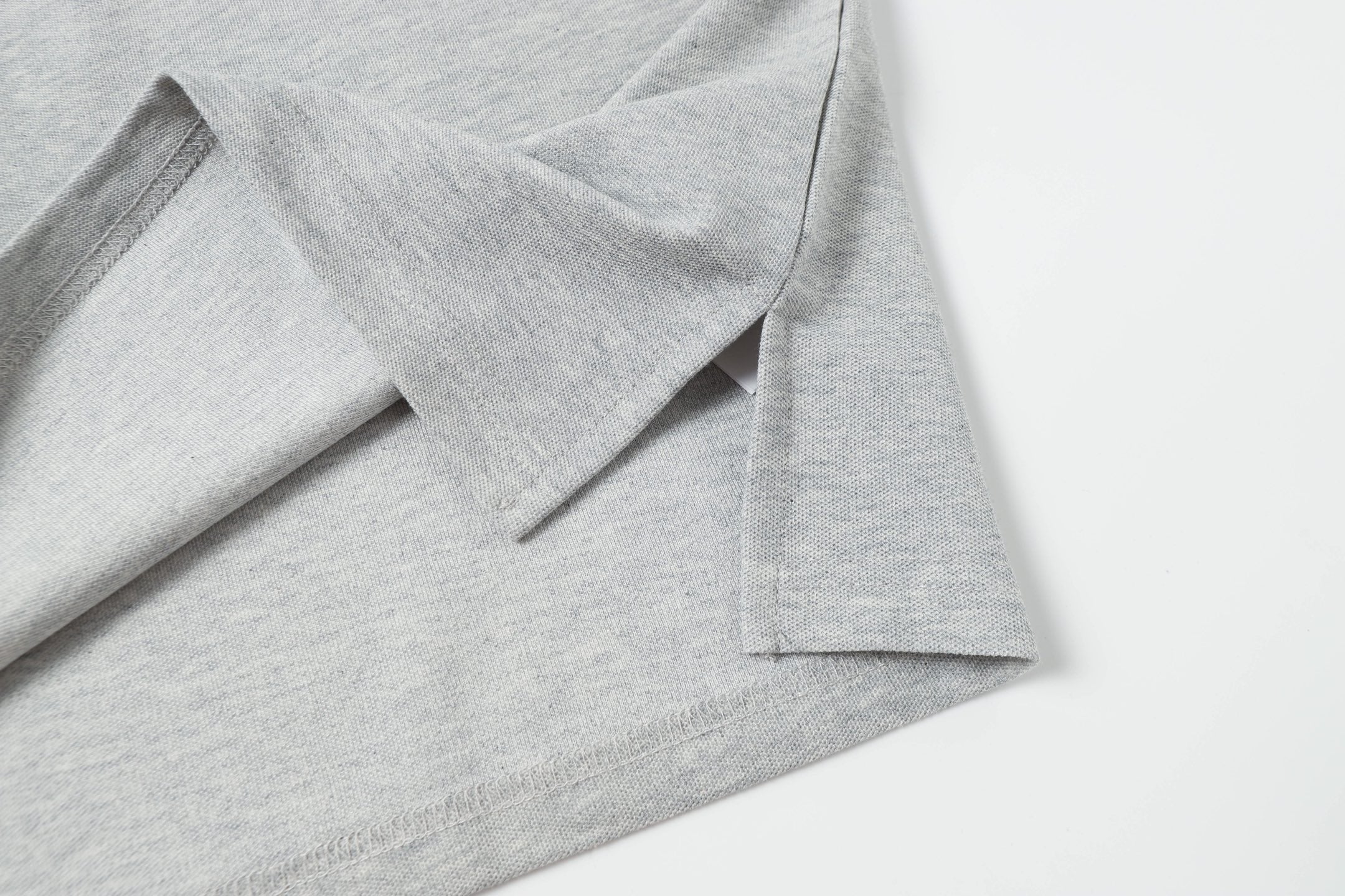 Light gray polo shirt hem with side seam and button placket detail
