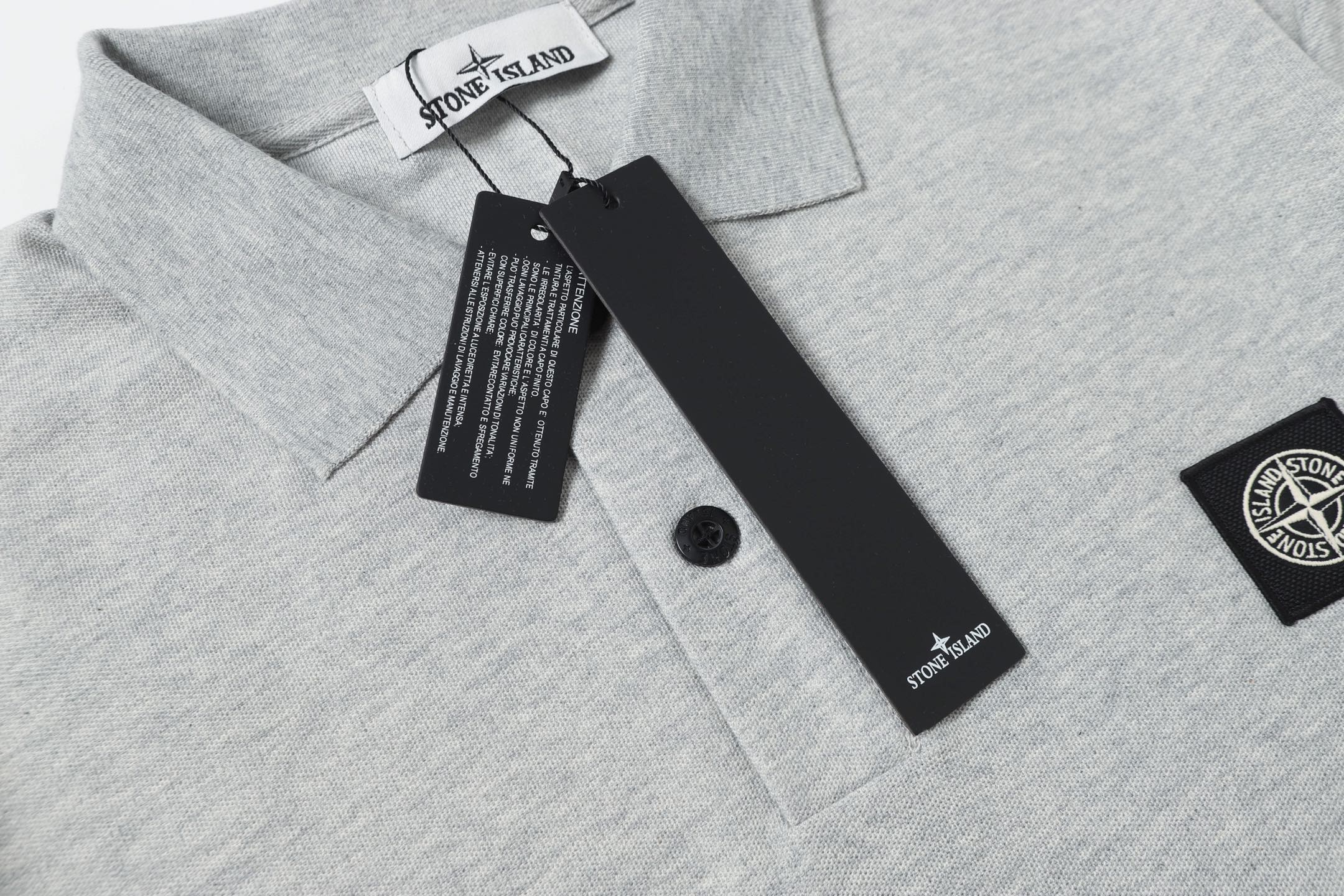 Light gray polo shirt collar and button placket with tag and logo patch
