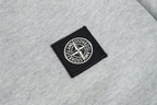 Embroidered black logo patch on light gray polo fabric