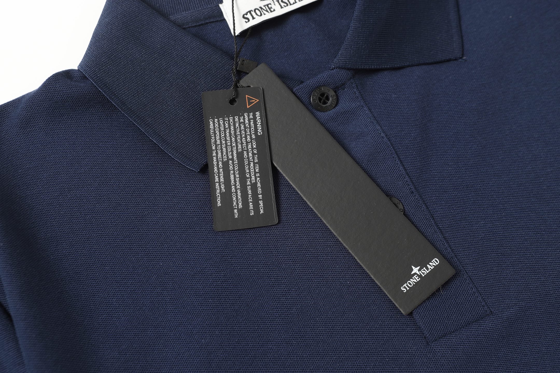 Navy polo shirt close-up with collar buttons and diagonal chest brand label