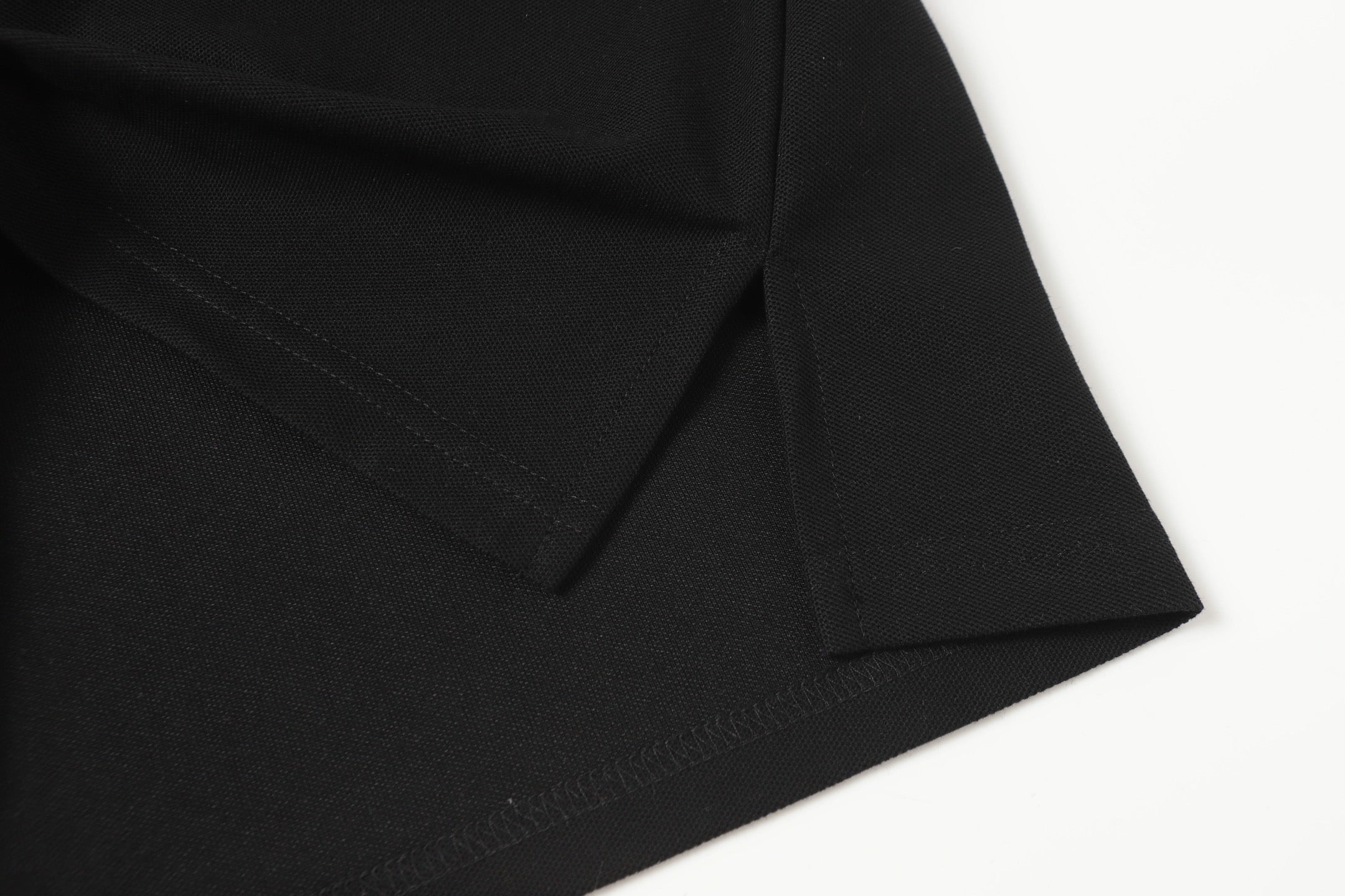 Black polo shirt side seam with stitched hem
