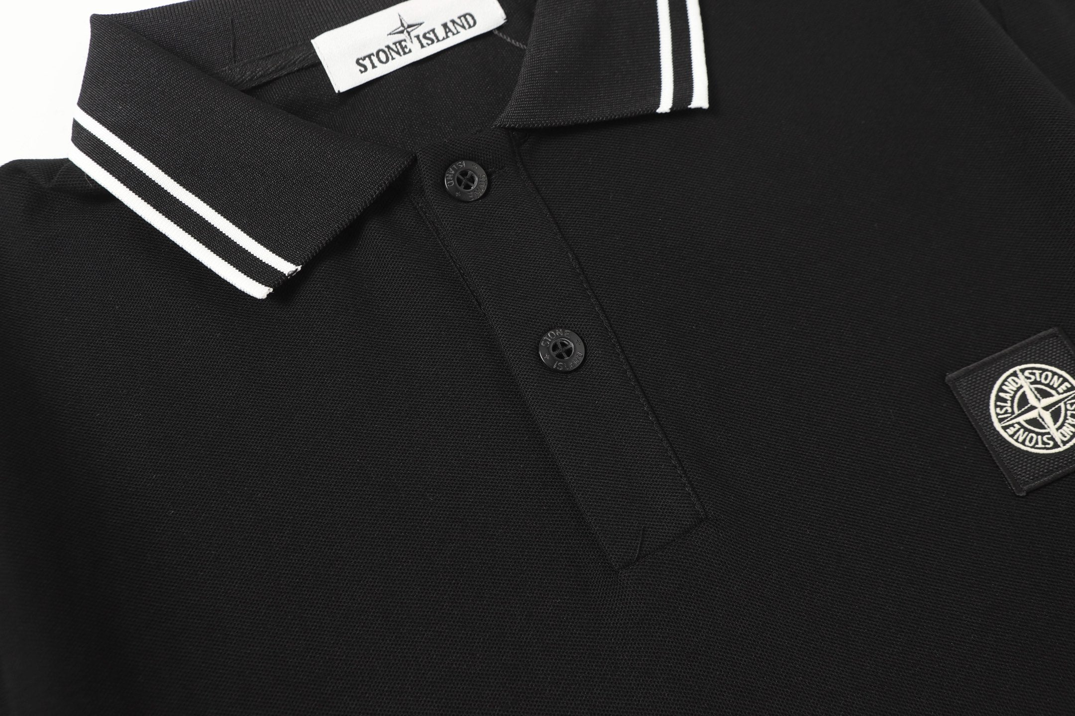 Black polo shirt with button placket and Stone Island shield patch