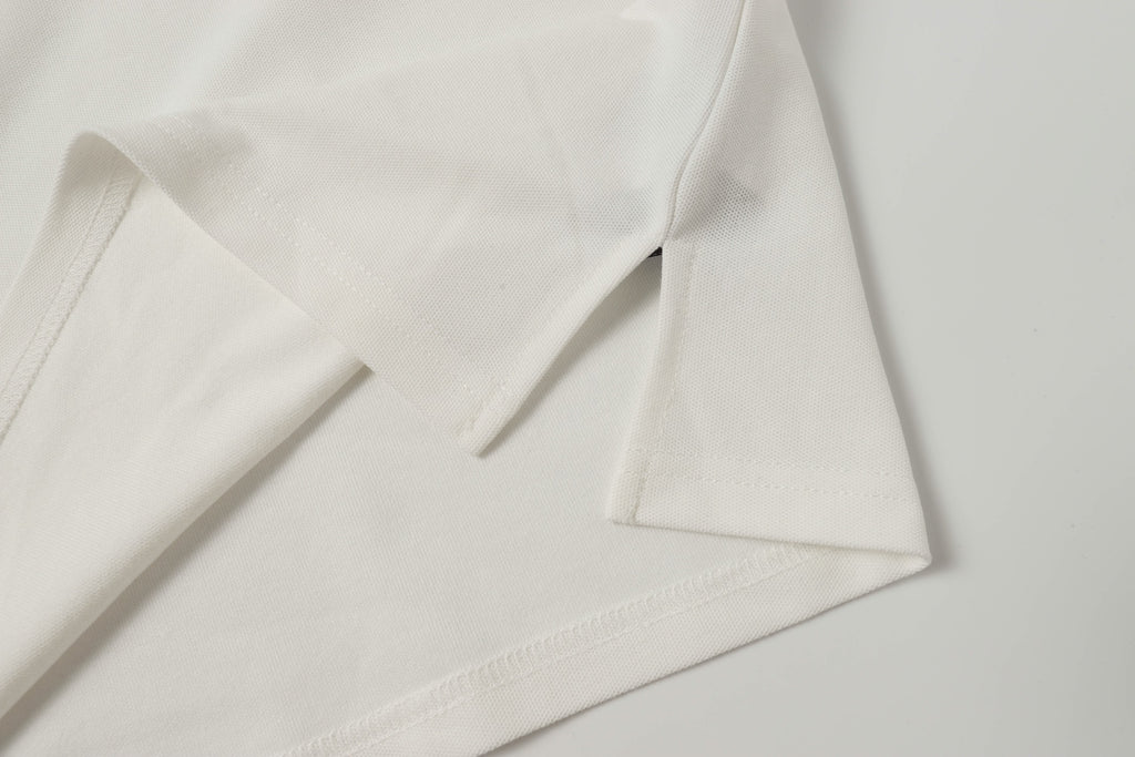White polo shirt fabric close-up with stitched hem and sleeve