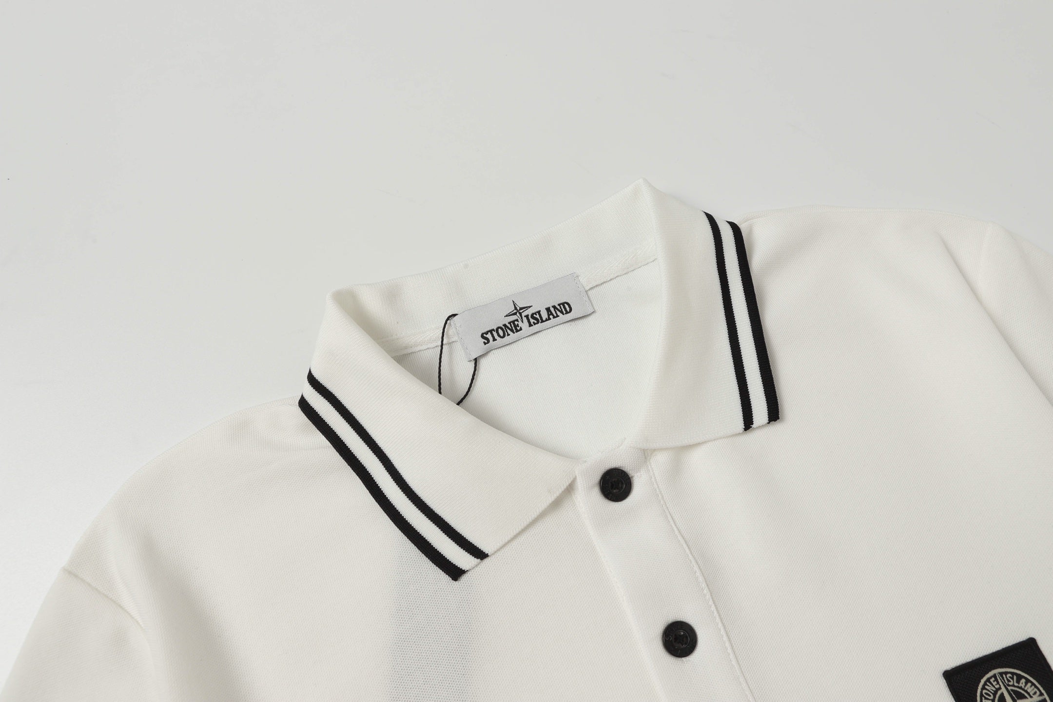 White polo shirt neckline with black striped collar and two-button placket
