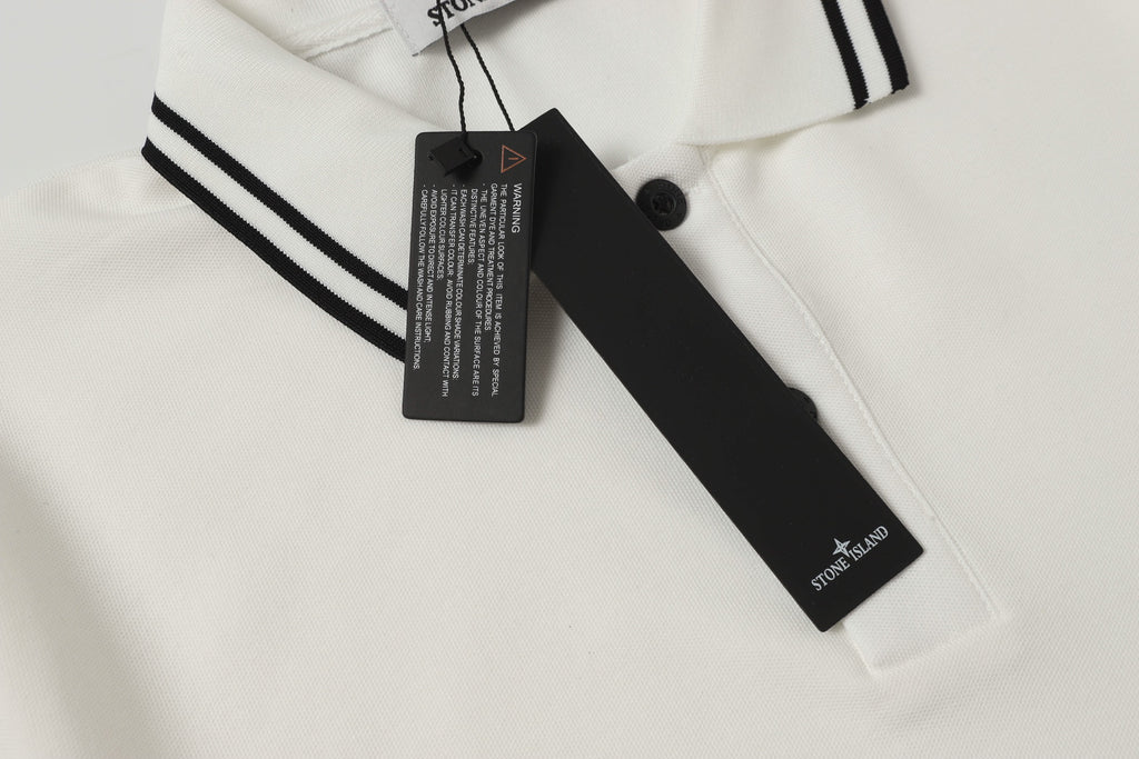 White polo shirt neckline detail with black button and hanging brand tag