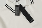 White polo shirt neckline detail with black button and hanging brand tag
