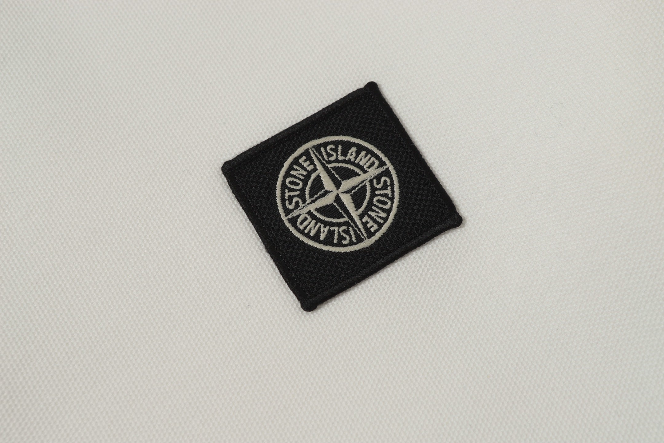 Black woven logo patch on white fabric