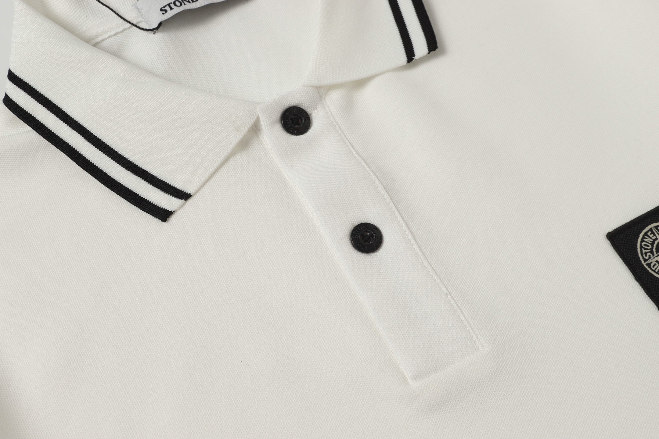 White polo shirt front with black buttons and partial sleeve stripe trim