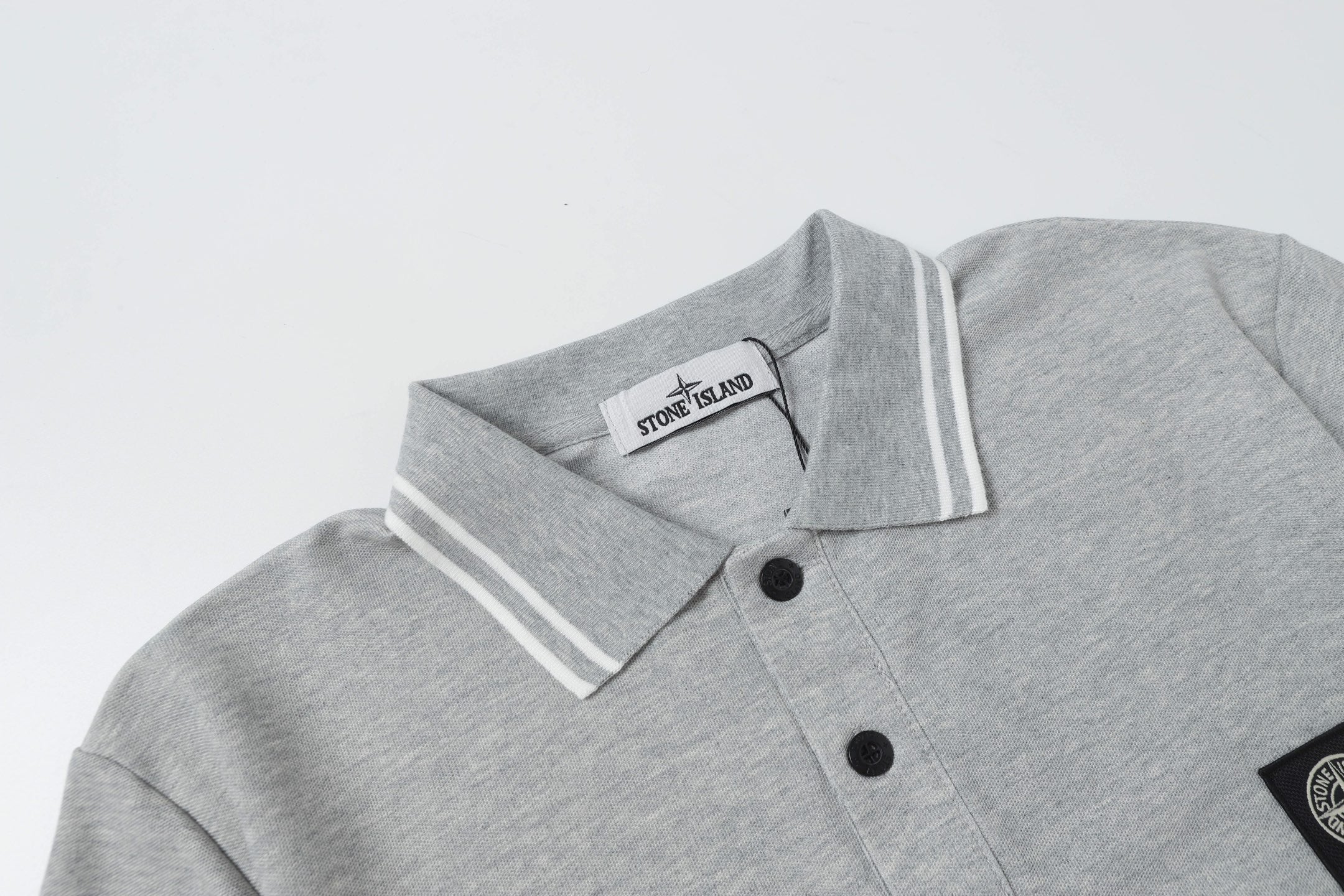 Light gray polo shirt neckline with two-button placket and striped collar