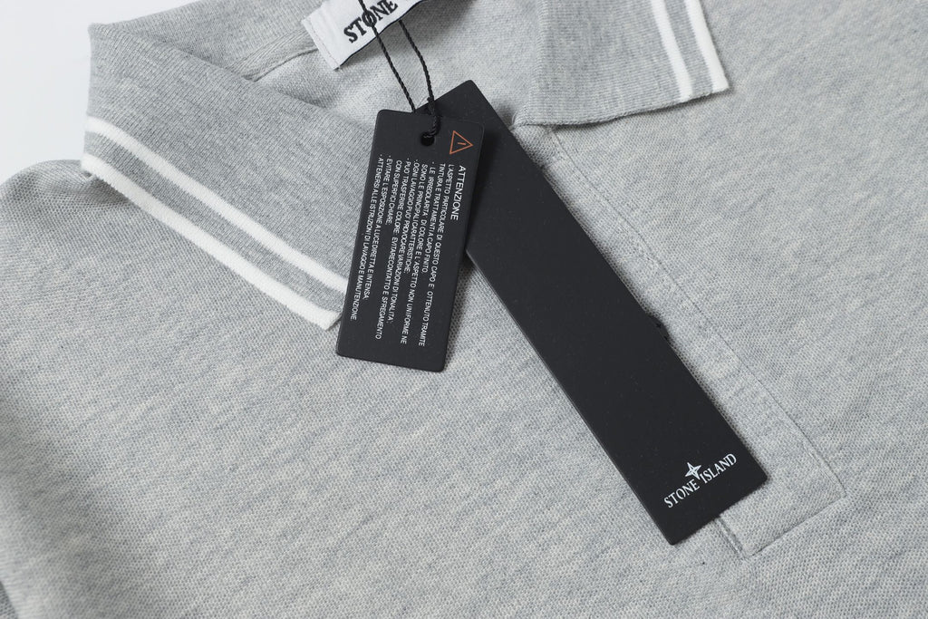 Light gray polo collar close-up with striped trim and black hang tag