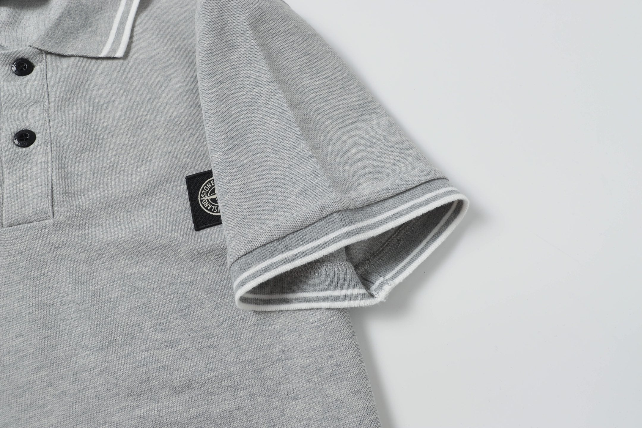 Light gray polo shirt sleeve cuff with striped ribbed trim