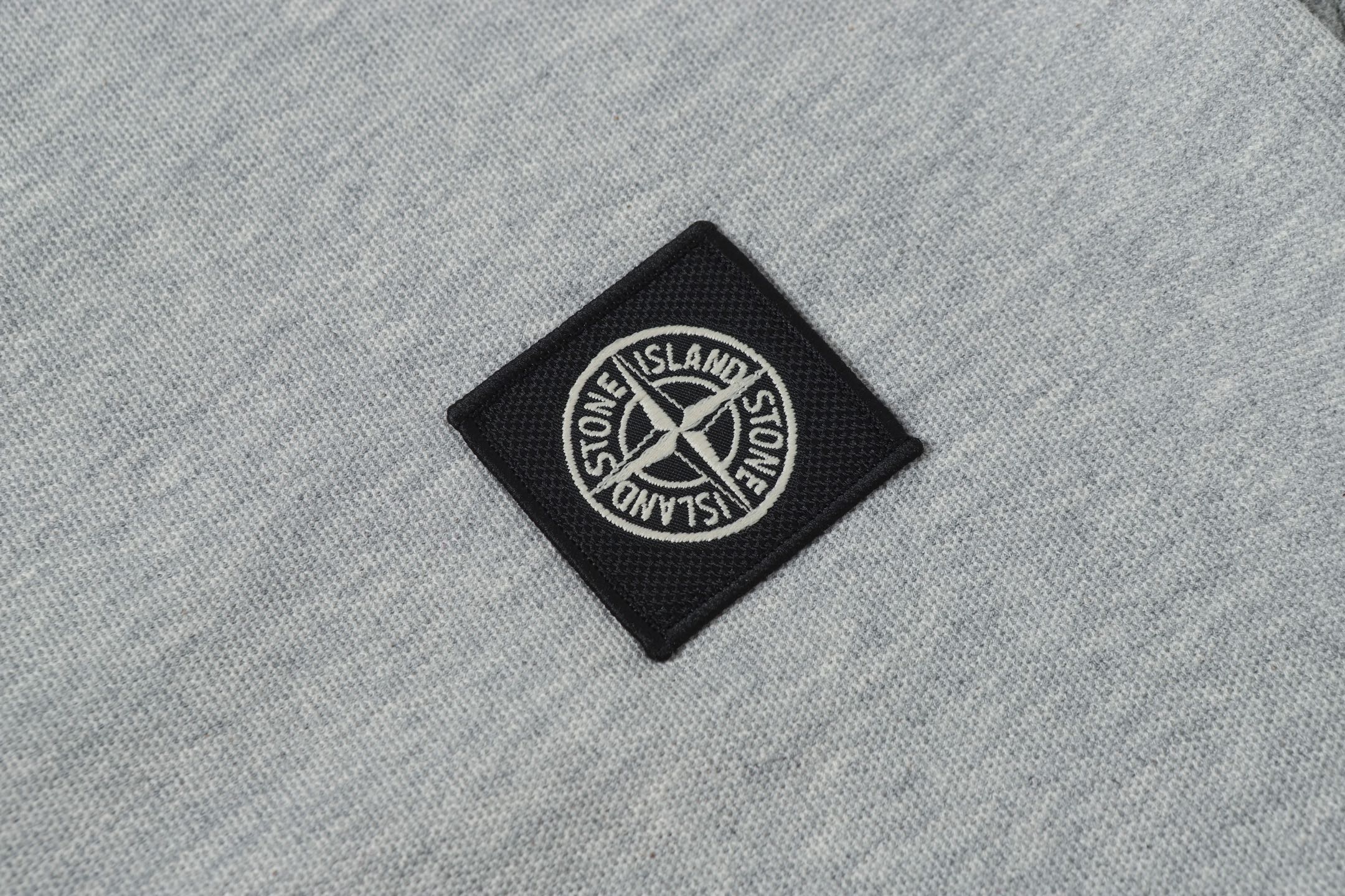 Stone Island patch logo on light gray polo fabric