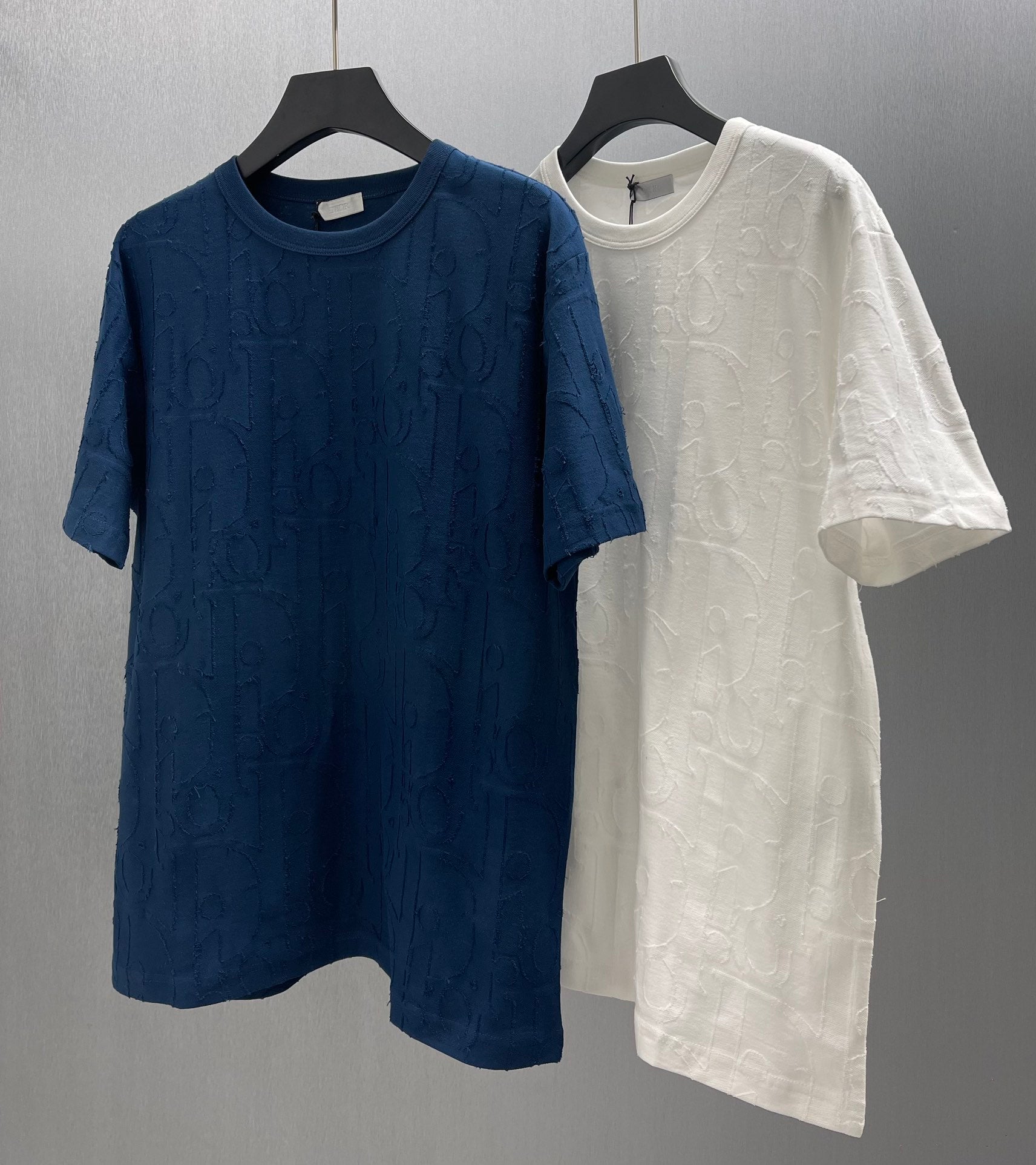 Blue and white Dior short-sleeve T-shirts with embossed pattern, hanging side by side