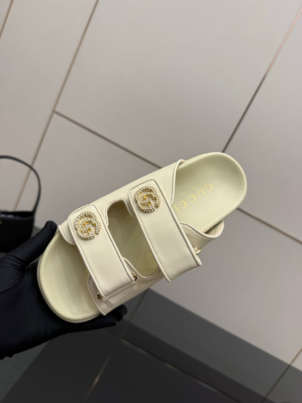 Gucci women's cream slide sandal showing cushioned footbed and decorative gold-tone buckle