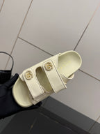 Gucci women's cream slide sandal showing cushioned footbed and decorative gold-tone buckle