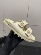 Gucci women's cream slide sandal on hand, featuring double straps and gold-tone buckle