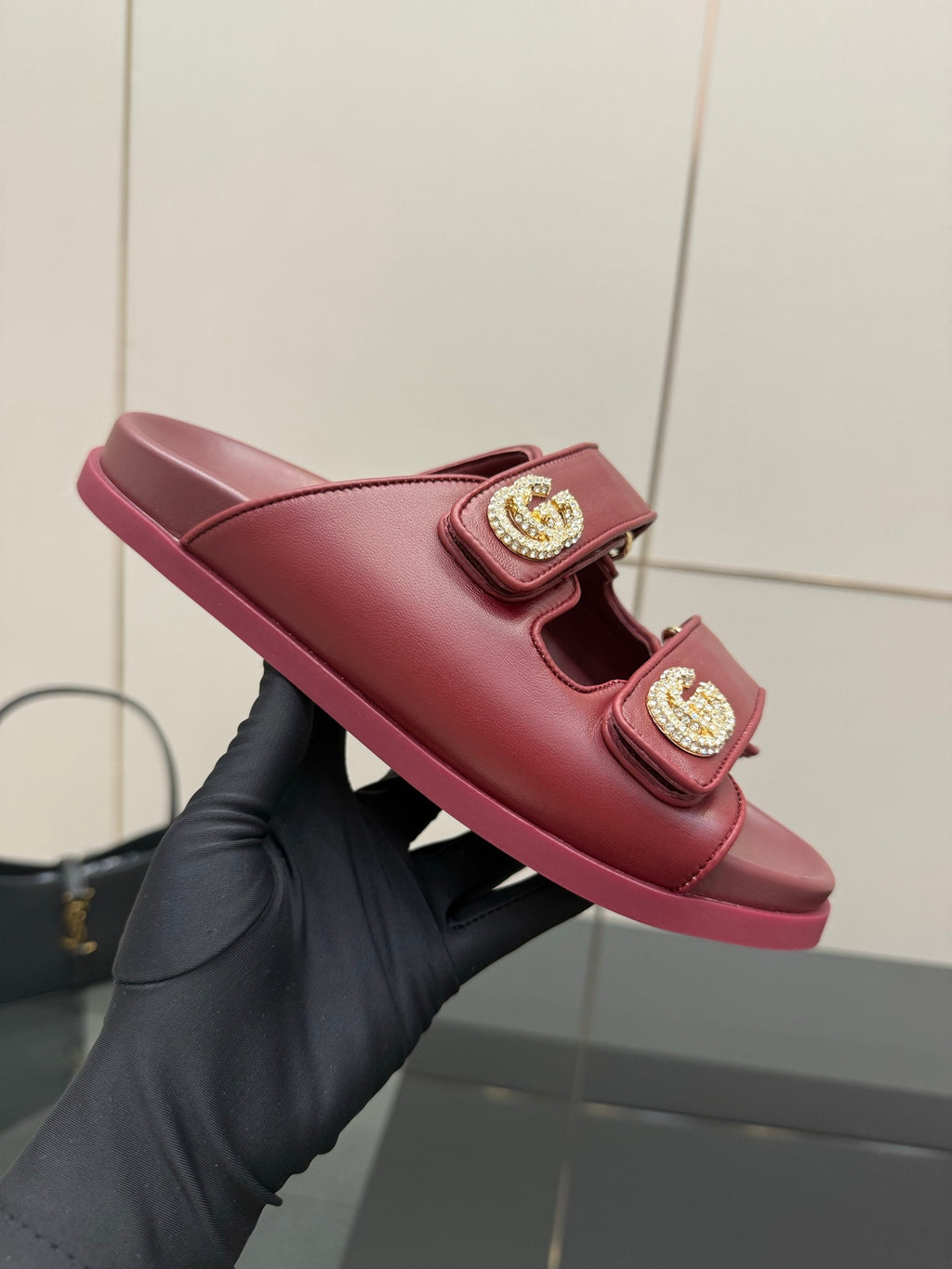 Red Gucci slide sandal, side view, with two straps and gold-tone logo buckles